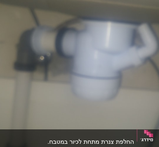 צינור פלסטיק לבן עם מחבר מתחת לכיור